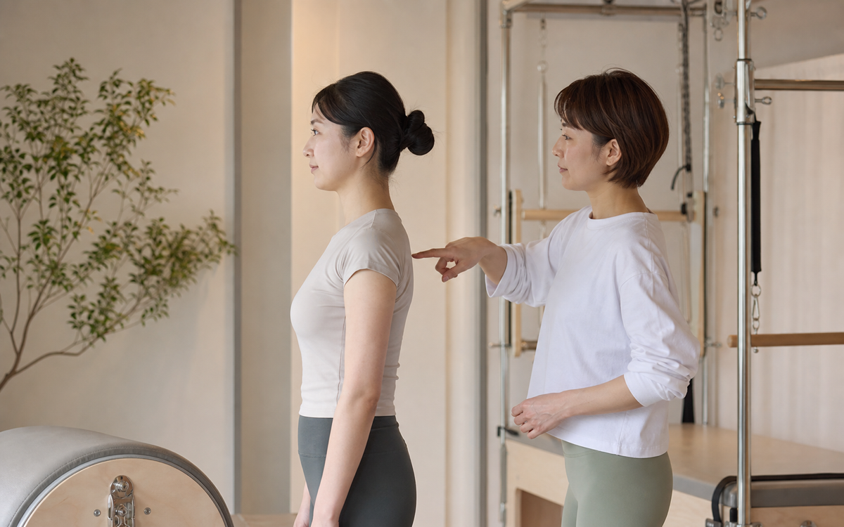 猫背や巻き肩が気になる方の姿勢を確認する女性インストラクター