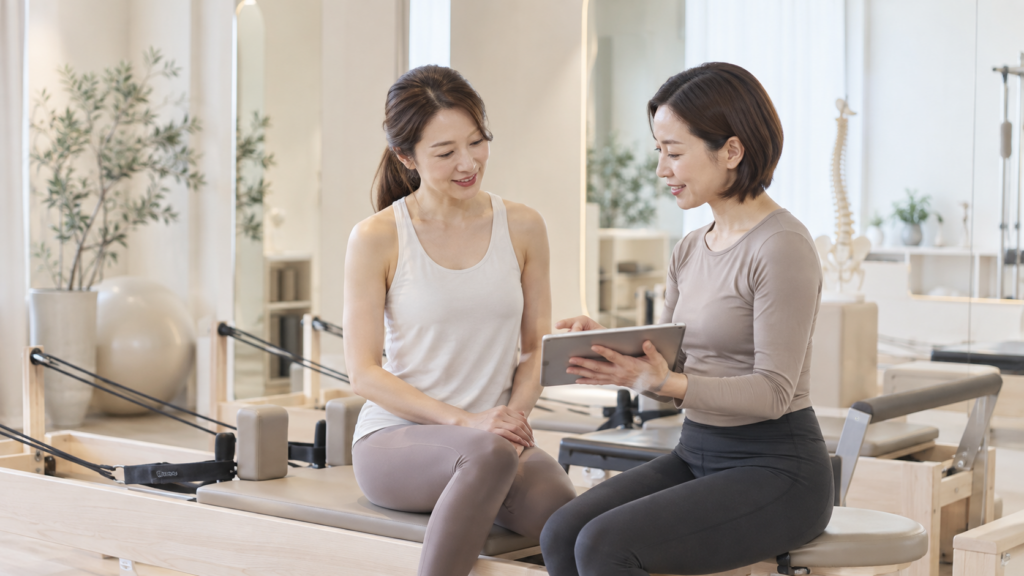 ピラティスを続けた身体の変化をトレーナーと確認する女性
